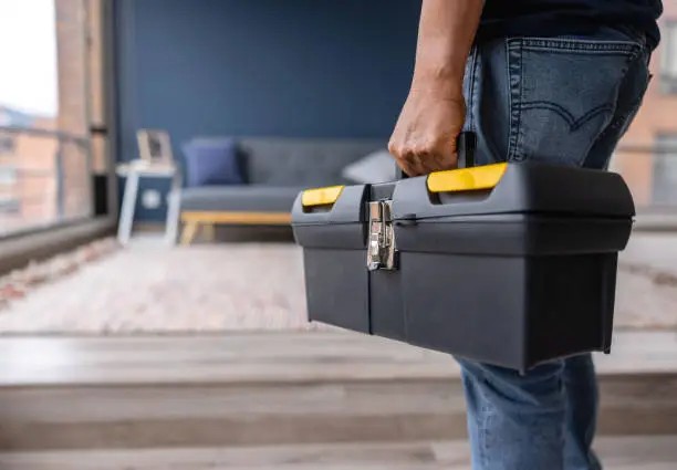 Handyman carrying a toolbox at home