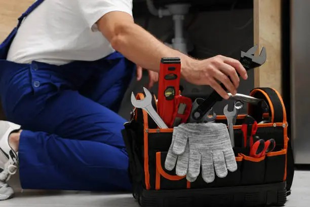 Worker reaching for a wrench from a well-organised tool bag