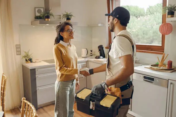 Homeowner shaking hands with a verified service professional in a bright kitchen